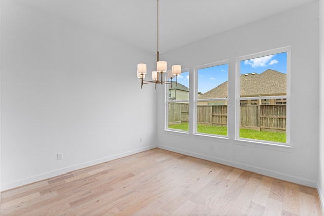 unfurnished dining area with a chandelier and light hardwood / wood-style floors