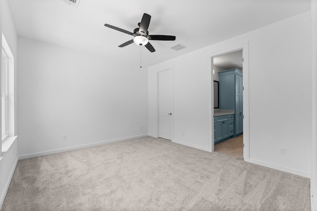 unfurnished bedroom with ensuite bathroom, light carpet, and ceiling fan