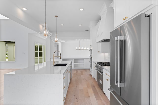 kitchen featuring sink, high quality appliances, hanging light fixtures, a large island, and white cabinets