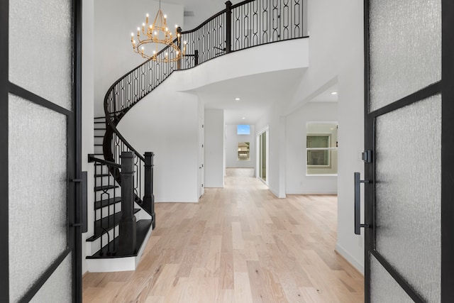 entryway featuring a towering ceiling and light wood-type flooring