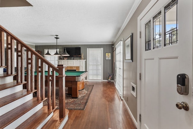 foyer entrance with crown molding, plenty of natural light, a fireplace, and dark wood-type flooring