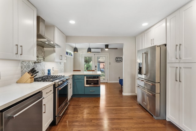 kitchen with wall chimney exhaust hood, white cabinetry, tasteful backsplash, an AC wall unit, and appliances with stainless steel finishes