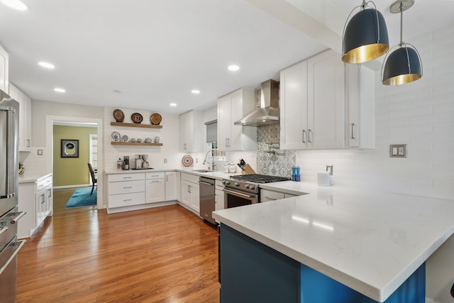 kitchen featuring pendant lighting, wall chimney range hood, white cabinetry, tasteful backsplash, and kitchen peninsula