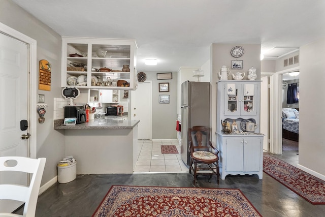 kitchen with stainless steel refrigerator, kitchen peninsula, and white cabinets