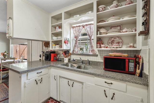 kitchen featuring stone counters, white cabinetry, sink, and backsplash