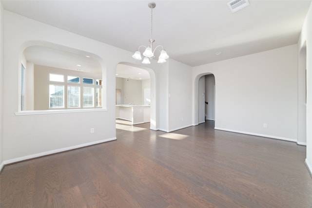 empty room with a chandelier and dark wood-type flooring