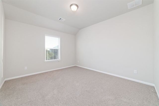 carpeted spare room with vaulted ceiling