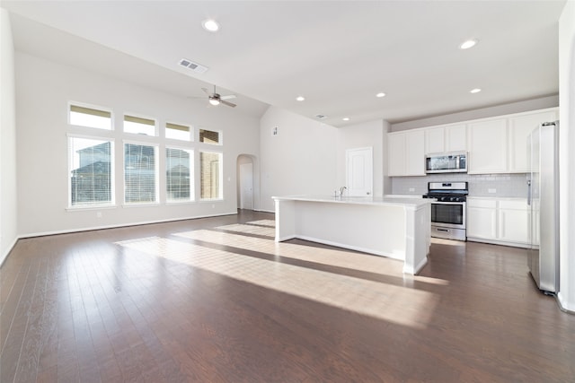 kitchen with dark hardwood / wood-style flooring, white cabinetry, stainless steel appliances, decorative backsplash, and a kitchen island with sink