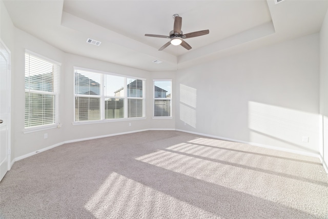 empty room featuring ceiling fan, carpet, and a raised ceiling