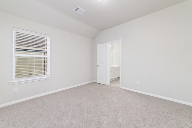 unfurnished room featuring lofted ceiling and light colored carpet