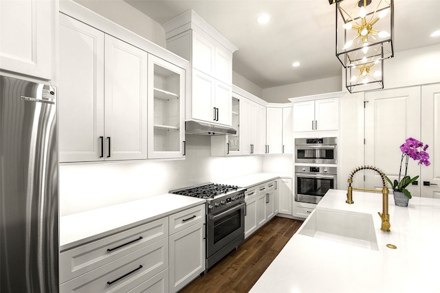 kitchen featuring dark wood-type flooring, hanging light fixtures, stainless steel appliances, sink, and white cabinetry