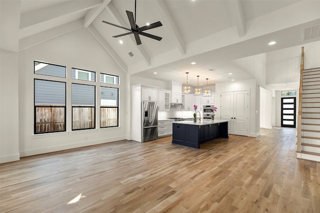 kitchen featuring hanging light fixtures, a healthy amount of sunlight, a center island with sink, white cabinets, and appliances with stainless steel finishes