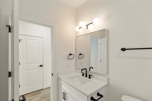 bathroom with vanity, toilet, and hardwood / wood-style floors