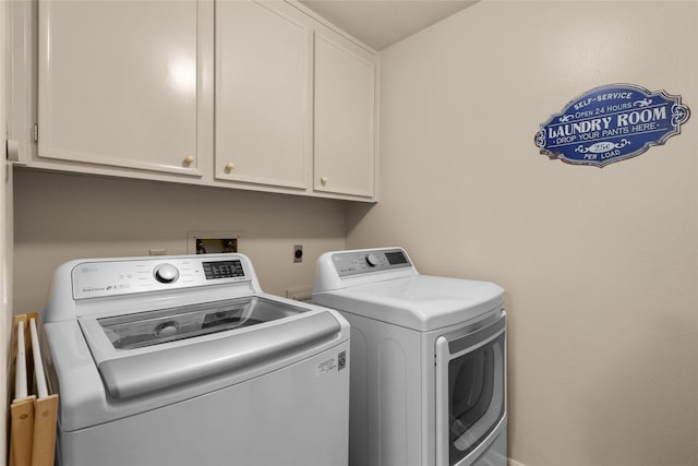 clothes washing area featuring cabinets and washing machine and clothes dryer