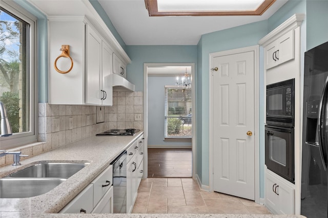 kitchen with sink, white cabinetry, light stone countertops, decorative backsplash, and black appliances