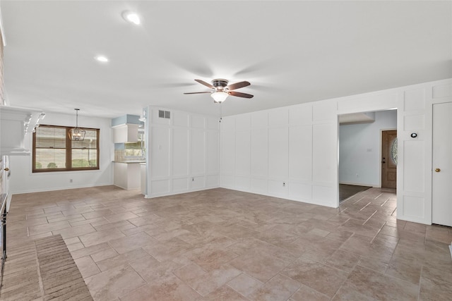 unfurnished living room featuring ceiling fan with notable chandelier