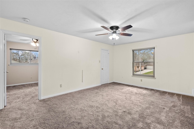 carpeted spare room featuring ceiling fan and plenty of natural light