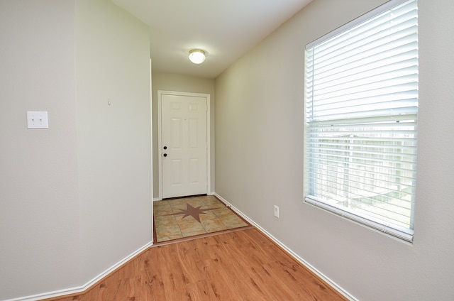 doorway featuring baseboards and light wood-type flooring