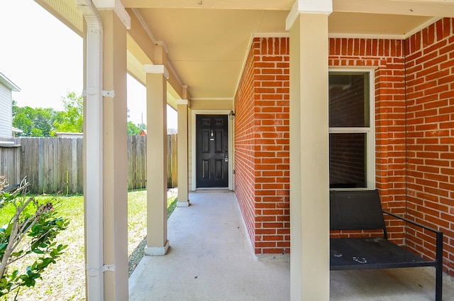 doorway to property featuring brick siding and fence