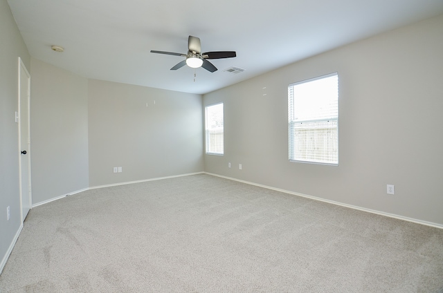 carpeted spare room with visible vents, baseboards, and ceiling fan