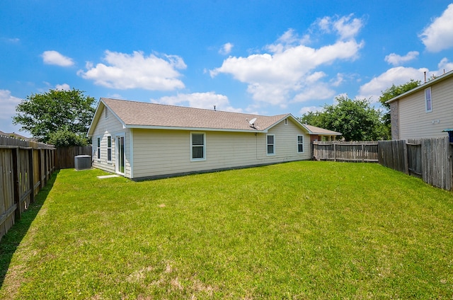 rear view of property featuring a yard, cooling unit, and a fenced backyard