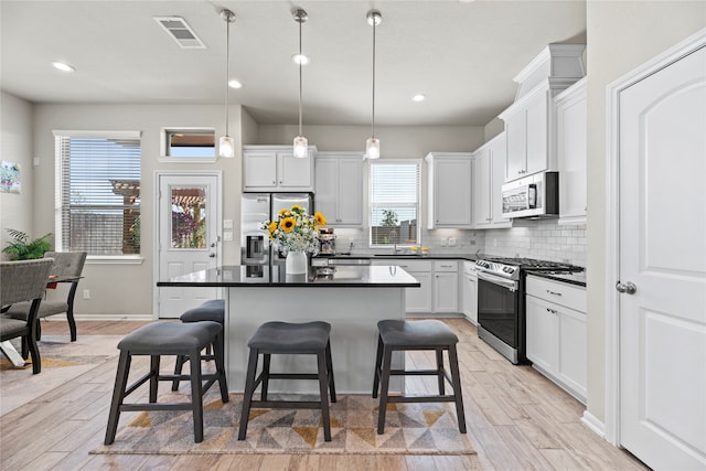 kitchen with a kitchen breakfast bar, light hardwood / wood-style flooring, and appliances with stainless steel finishes