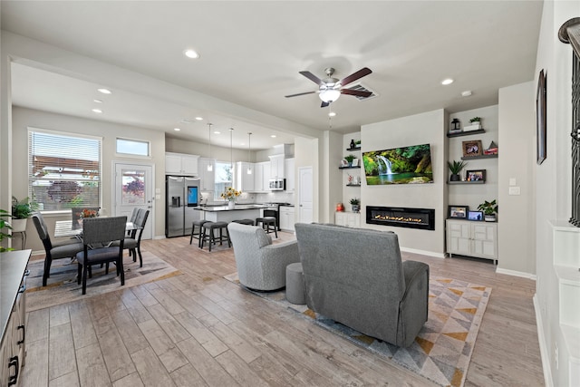 living room featuring ceiling fan and light hardwood / wood-style flooring