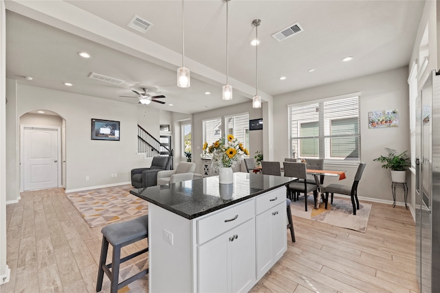 kitchen featuring a healthy amount of sunlight, white cabinetry, a breakfast bar, and a kitchen island