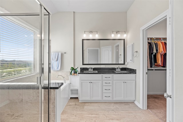 bathroom with wood-type flooring, vanity, and shower with separate bathtub