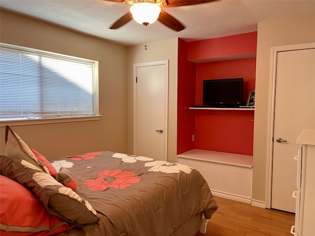 bedroom with ceiling fan, a textured ceiling, and light hardwood / wood-style flooring