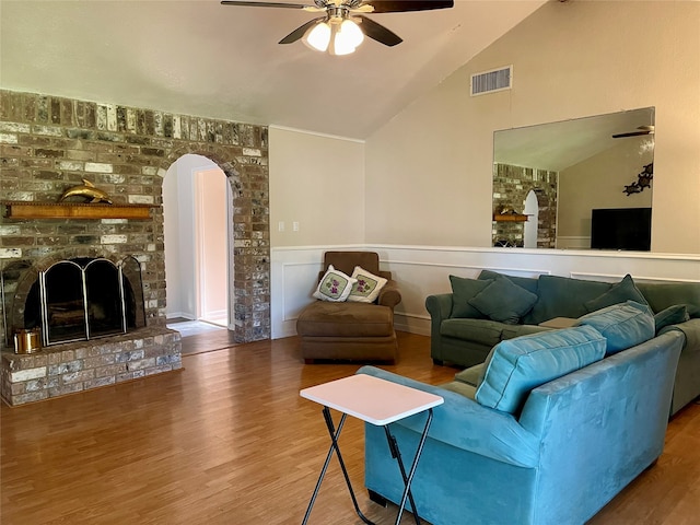 living room with lofted ceiling, a brick fireplace, wood-type flooring, and ceiling fan