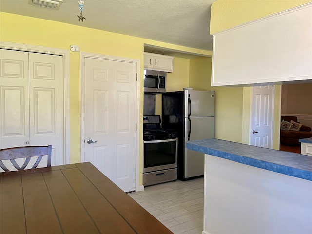 kitchen with white cabinetry, stainless steel appliances, and a textured ceiling