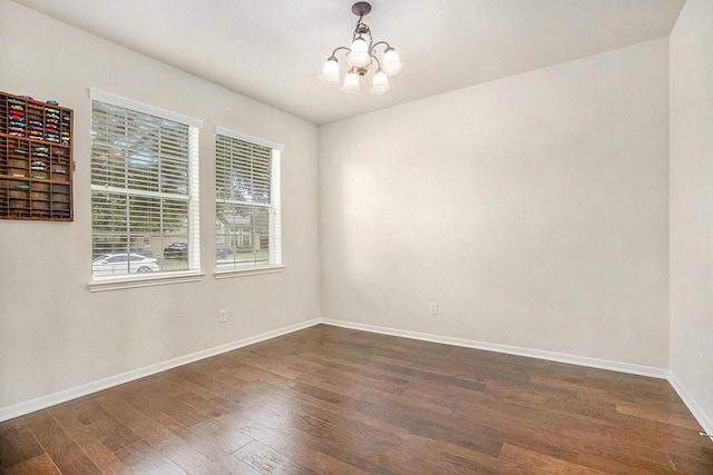 spare room with a chandelier, dark hardwood / wood-style floors, and plenty of natural light