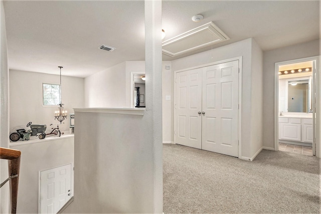 corridor with light colored carpet and an inviting chandelier