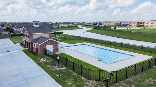 view of swimming pool featuring a yard and a water view