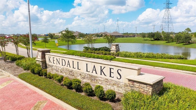 community sign featuring a water view and a yard