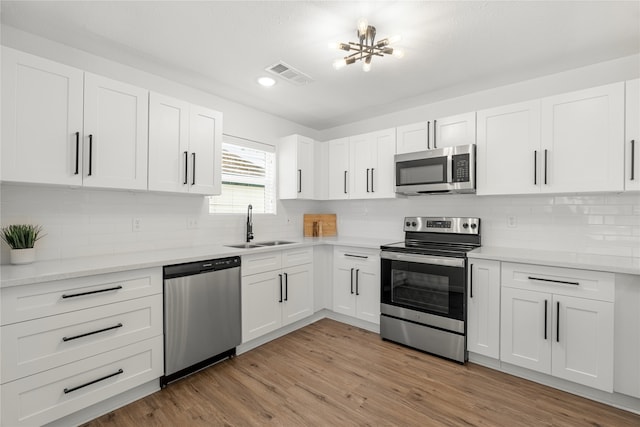 kitchen with sink, appliances with stainless steel finishes, light wood-type flooring, and white cabinetry