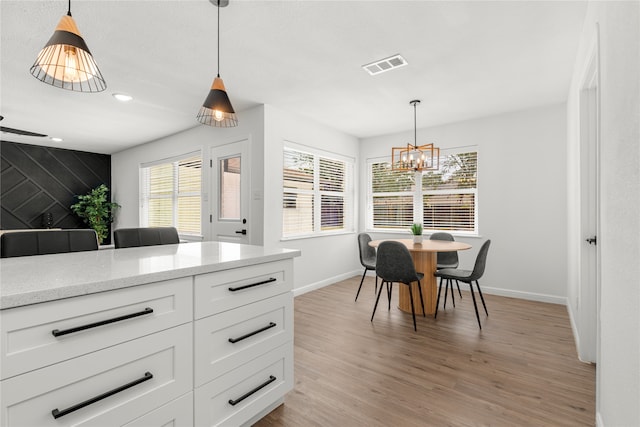 kitchen with hanging light fixtures, white cabinetry, and light hardwood / wood-style flooring