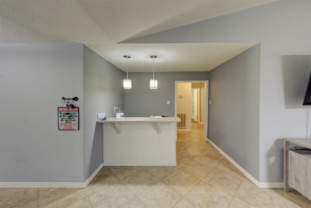 kitchen featuring a textured ceiling, kitchen peninsula, vaulted ceiling, decorative light fixtures, and a breakfast bar