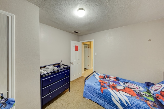 bedroom featuring light carpet and a textured ceiling