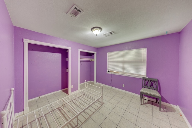 unfurnished bedroom featuring a closet, a textured ceiling, and light tile patterned floors