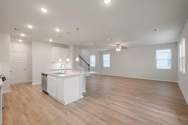 kitchen with sink, decorative light fixtures, a kitchen island with sink, and white cabinets