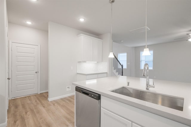 kitchen featuring sink, white cabinetry, stainless steel dishwasher, pendant lighting, and light hardwood / wood-style floors