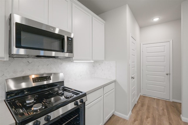 kitchen featuring white cabinetry, appliances with stainless steel finishes, light hardwood / wood-style floors, and backsplash