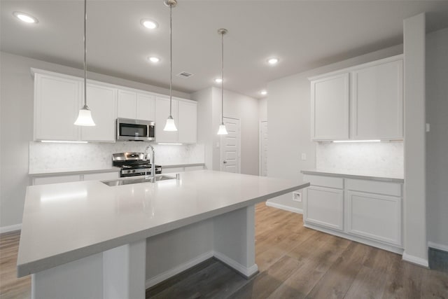 kitchen with stainless steel appliances, sink, a center island with sink, and white cabinets