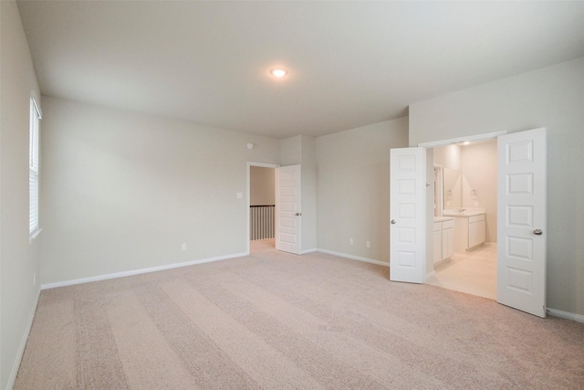 unfurnished bedroom featuring connected bathroom and light carpet