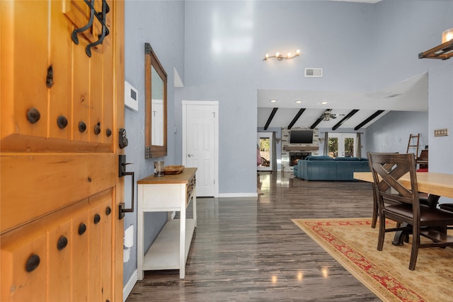 foyer entrance with beam ceiling, high vaulted ceiling, dark wood-type flooring, and a fireplace