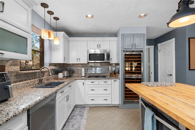 kitchen featuring backsplash, sink, black appliances, beverage cooler, and white cabinets