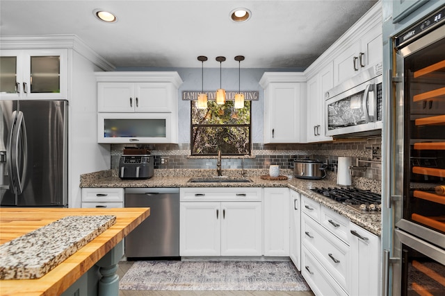 kitchen with sink, stainless steel appliances, dark stone counters, white cabinets, and decorative backsplash