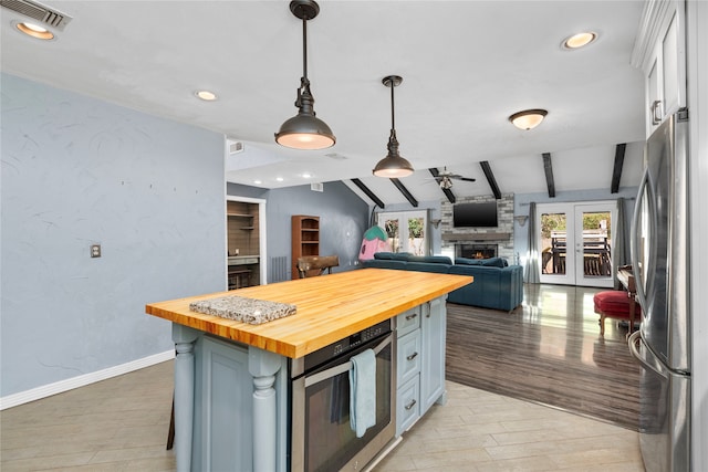 kitchen with wood counters, lofted ceiling with beams, a center island, white cabinetry, and stainless steel appliances